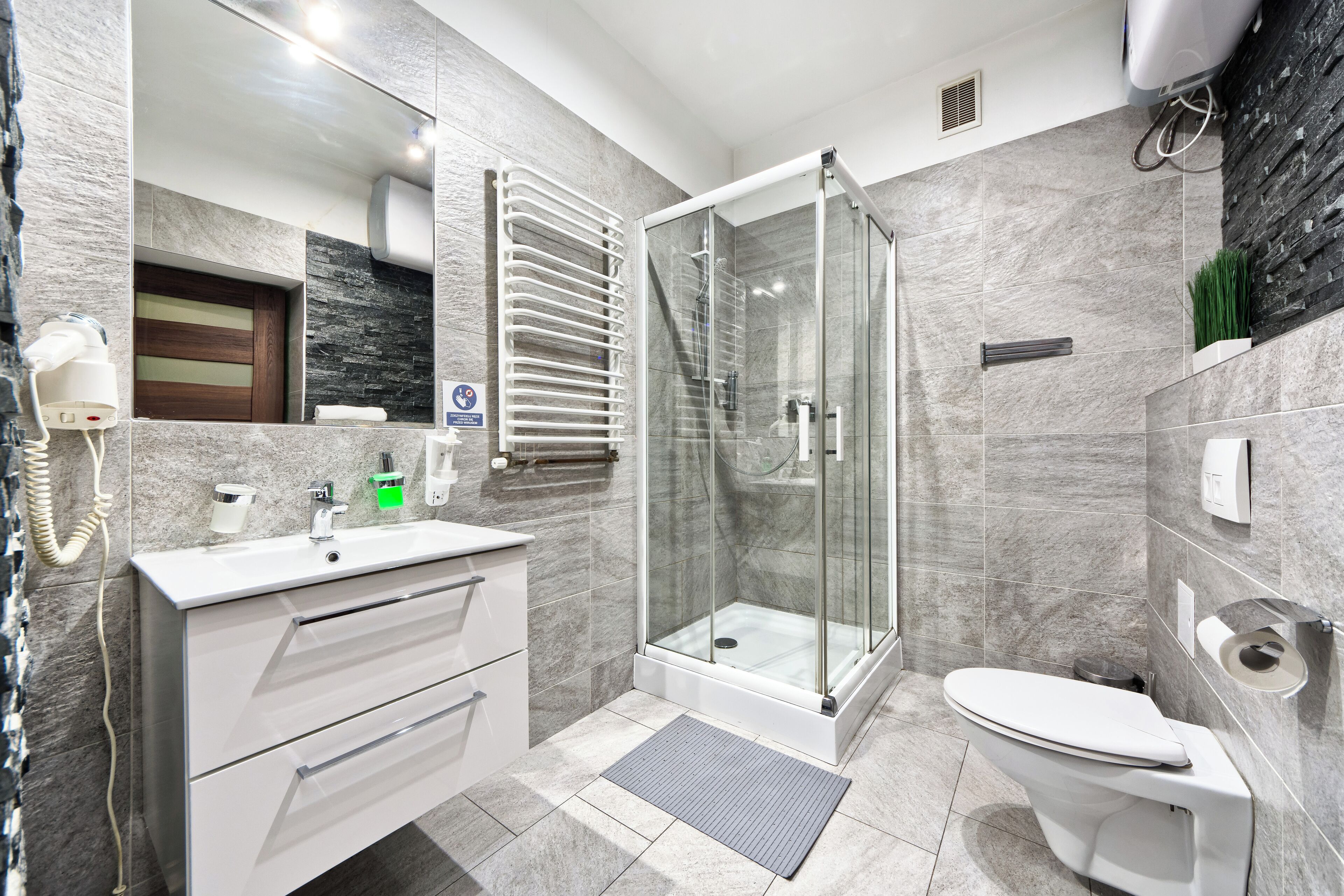Un baño moderno con ducha de vidrio, lavamanos blanco y retrete.