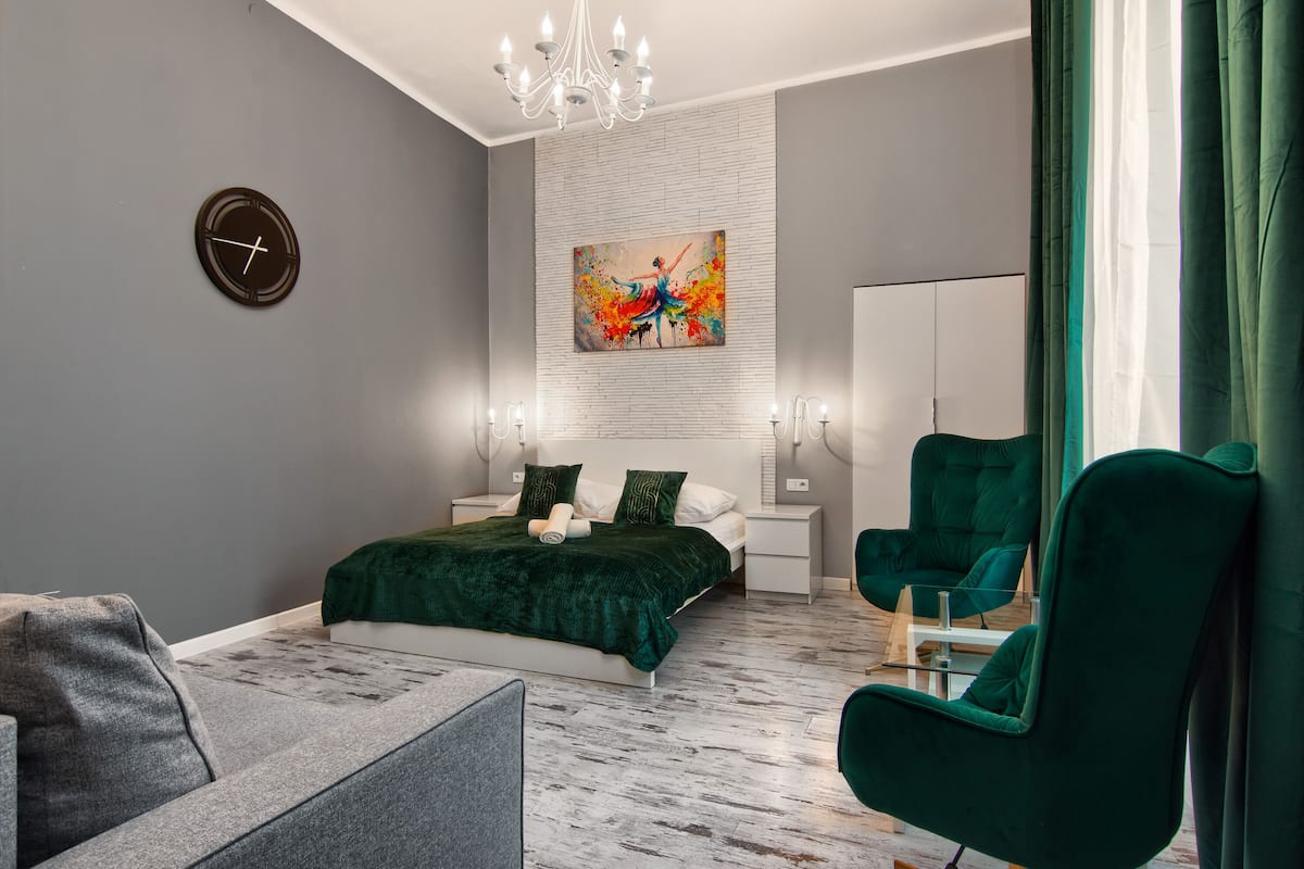 Ein modernes Schlafzimmer mit Bett, grünem Sessel und einem Bild an der Wand.