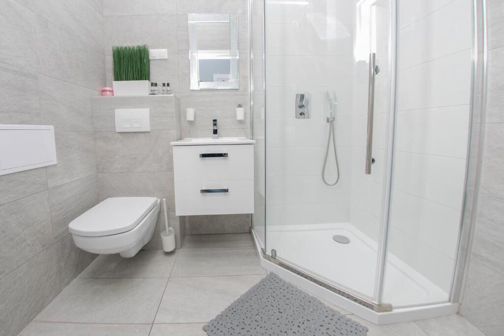 Un baño moderno con inodoro, lavamanos y ducha con mampara de vidrio.