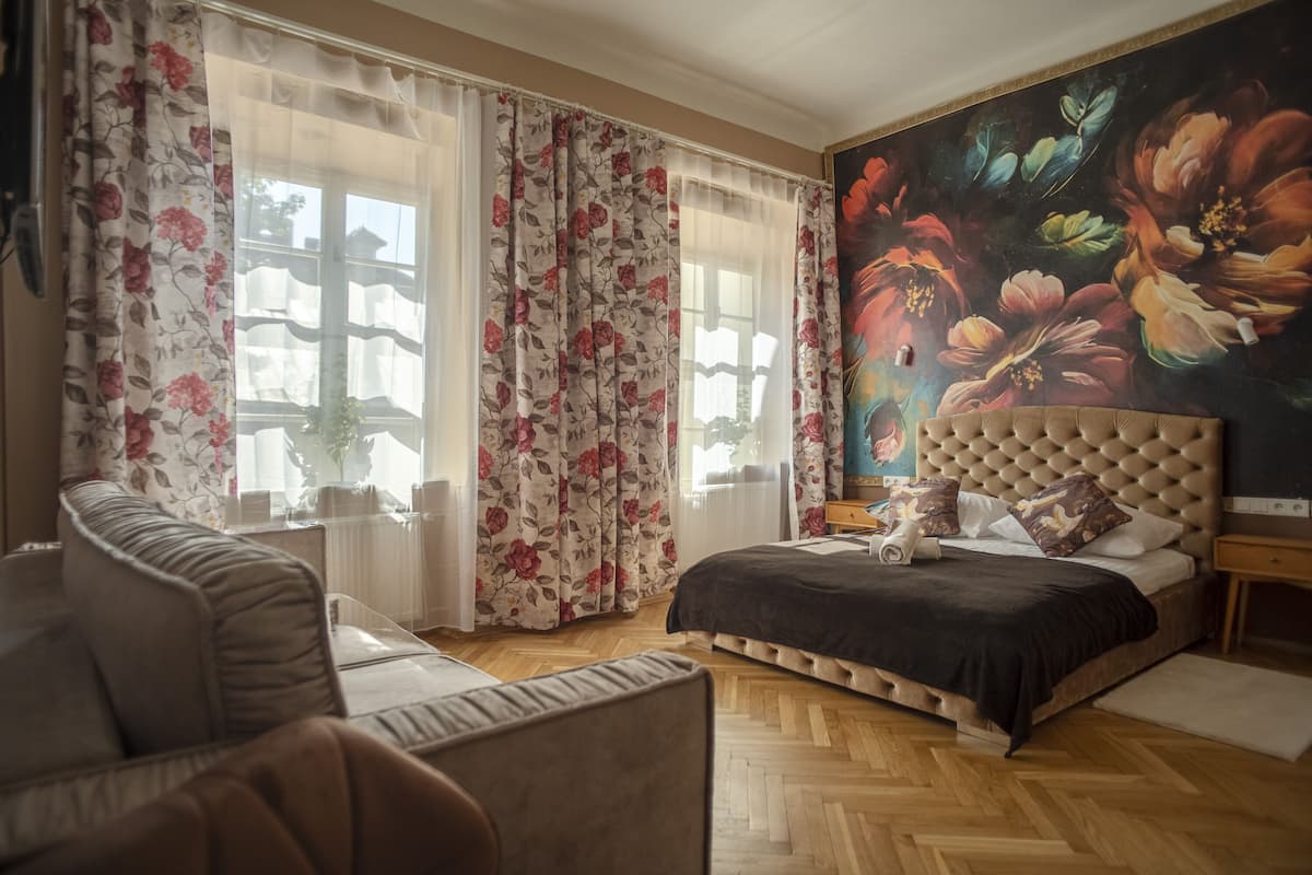 Ein Schlafzimmer mit einem großen Bett, einer Couch und einem Blumenbild.