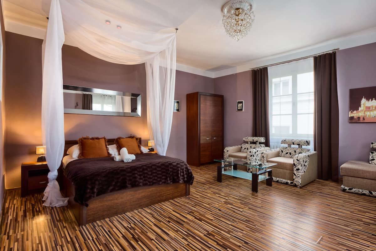 Ein Schlafzimmer mit Himmelsbett, Kleiderschrank, Sofagarnitur und einer Chandelier.