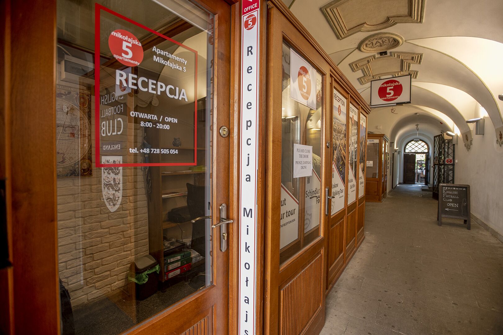 Zona de recepción con un cartel que indica la mesa de recepción, un número de teléfono y el horario de atención.