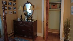 Una habitación con un aparador de madera, dos lámparas de pared, un espejo y un armario con estantes.