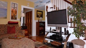 Una sala de estar con televisión, sofá, mesa de centro y una planta.