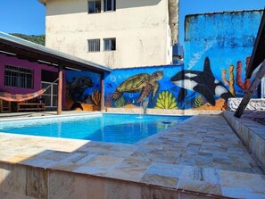 A swimming pool with a mural of marine life on the adjacent wall. - Hospedaria Antídoto (Guarujá)