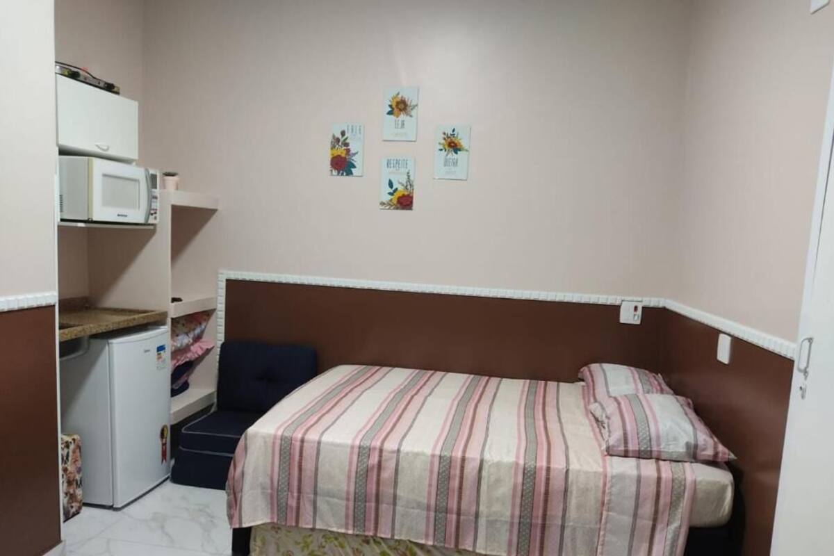 Une petite chambre compacte équipée d’un lit, d’un four à micro-ondes et d’un réfrigérateur.