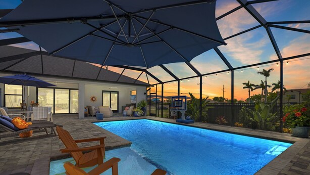 Una piscina con una veranda coperta, arredi da esterno e vista sul tramonto.