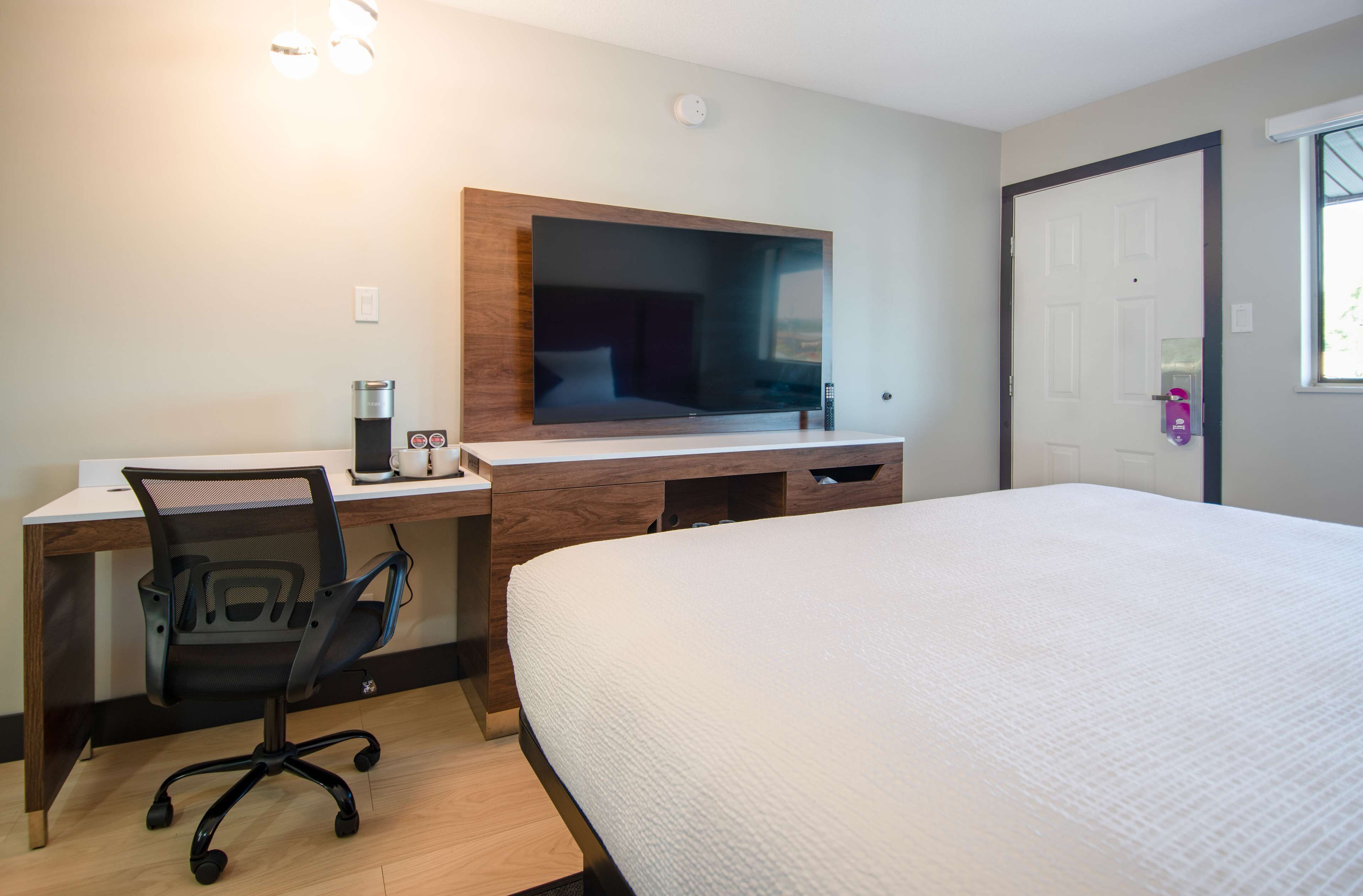 A hotel room with a bed, a desk with a chair, a television, and a coffee maker.