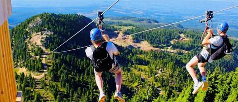 Two people bungee jumping with a scenic mountain view in the background.