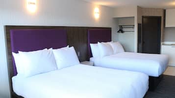 A hotel room with two beds, a wooden headboard, a small table, and a wardrobe.