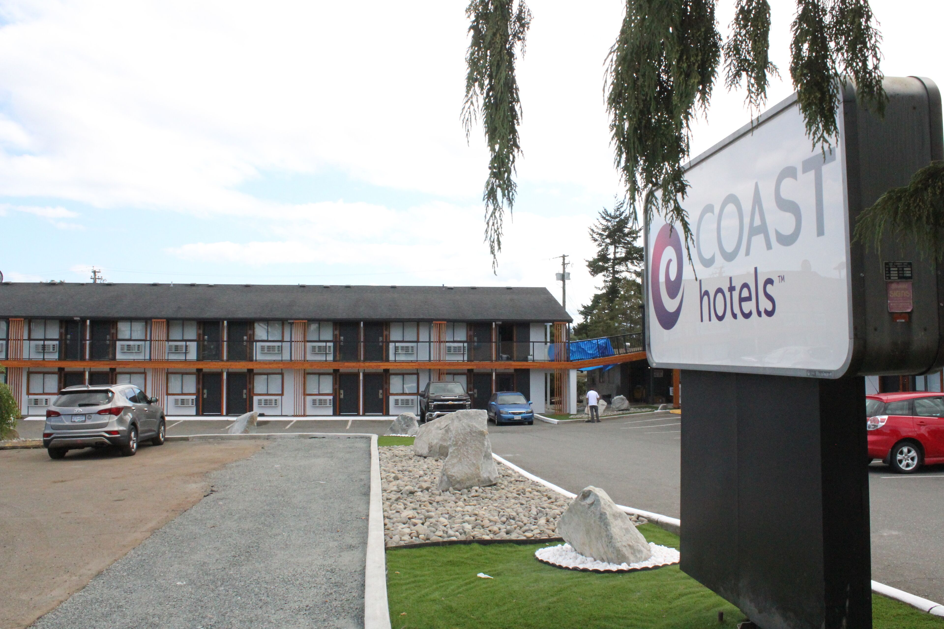 Un hotel dal design moderno, con parcheggio e un cartello con la scritta Coast Hotels.