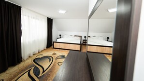 A modern hotel room with a large bed, a bedside table, a mirror, and a window with curtains. - Casa Câmpulungeană (Campulung Moldovenesc)