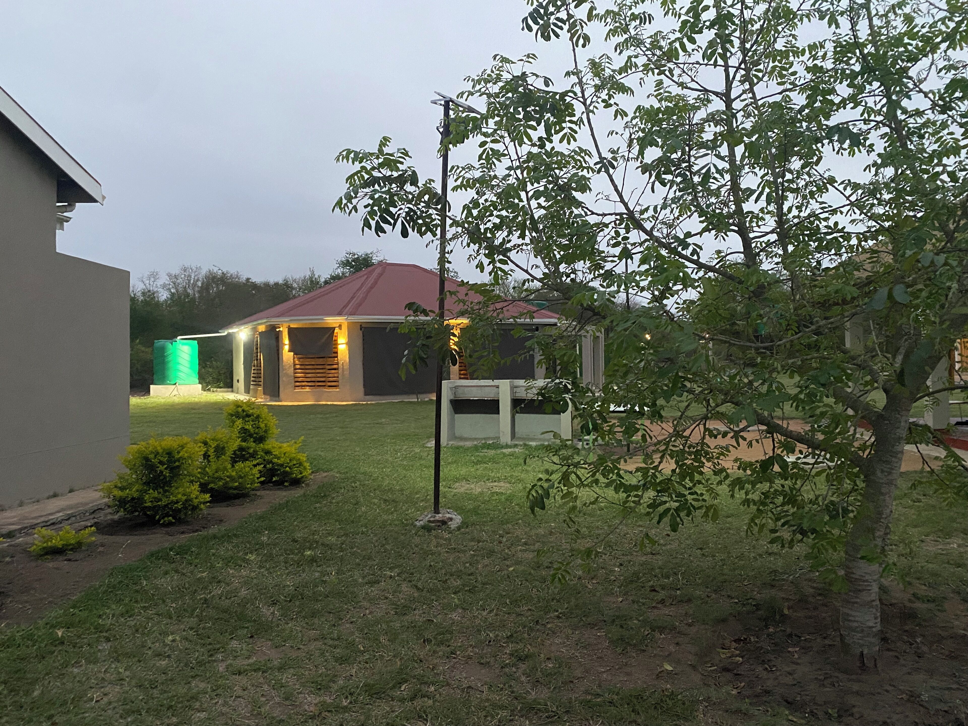 Un barrio residencial con una casa, un tanque de agua verde y un árbol.