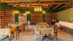 A restaurant with wooden beams, green walls, and tables set for dining. - Wanakah Estate Guesthouse (Mpaka)