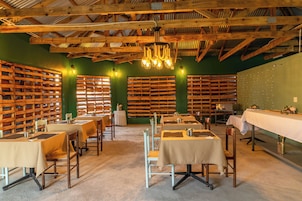 Un restaurante con vigas de madera, paredes verdes y mesas preparadas para comer.