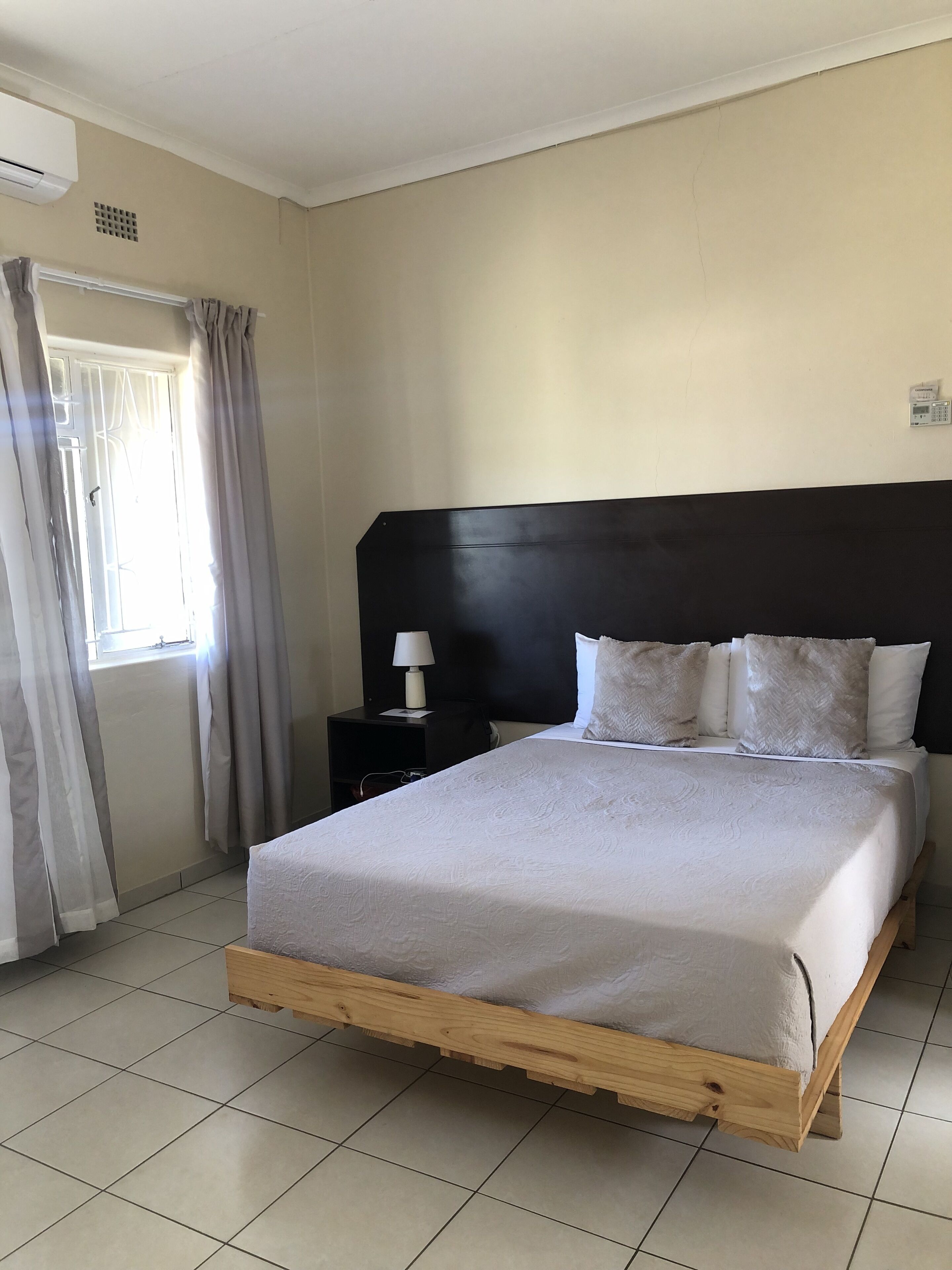 Une chambre à coucher avec un cadre de lit en bois, une tête de lit noire et une table de chevet avec une lampe.