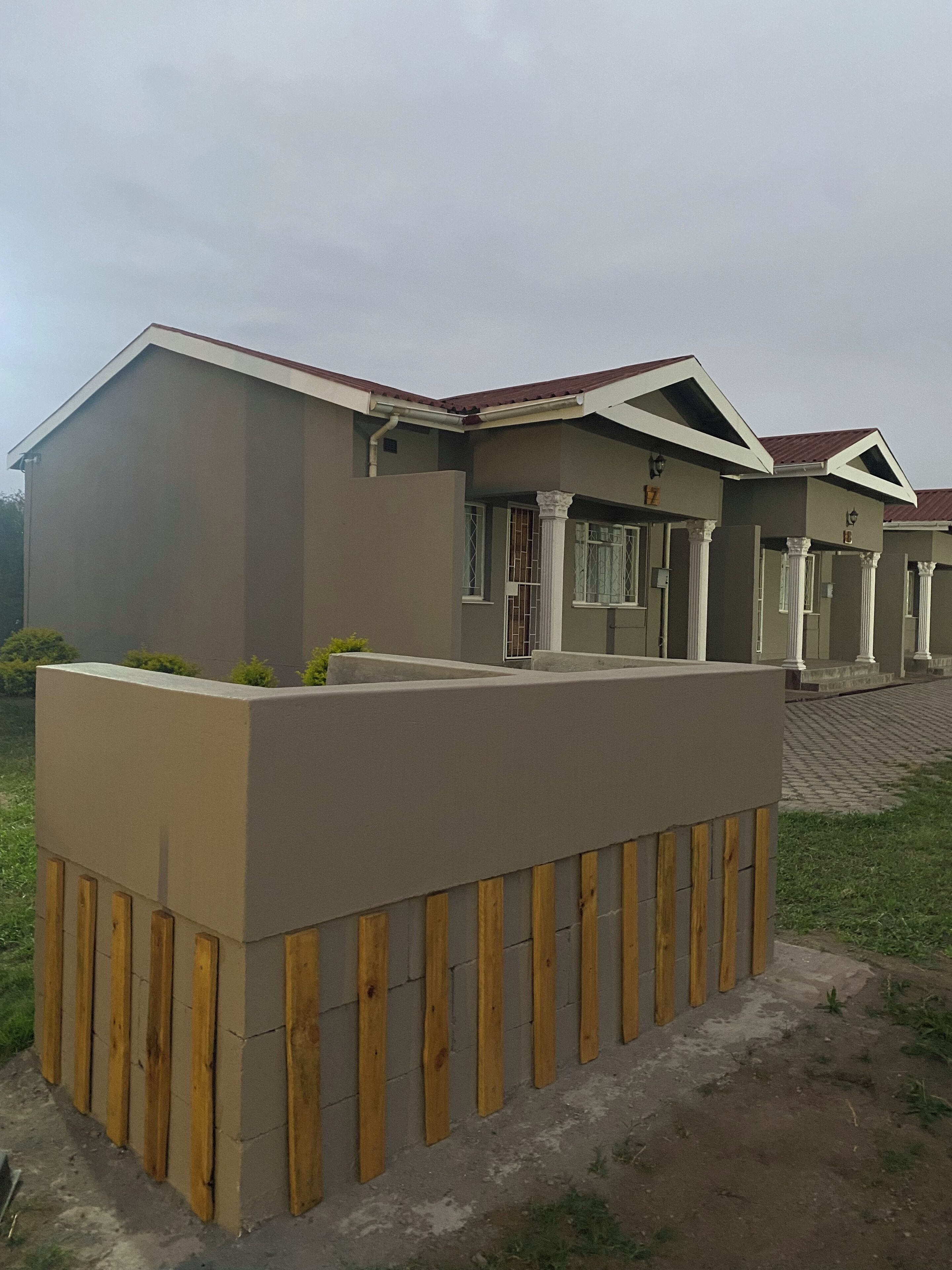Una casa moderna con techo plano, un porche con columnas y un pequeño jardín.