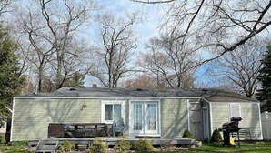 Ein Bungalow mit Terrasse, einer Schiebetür und einer kleinen angebauten Garage.
