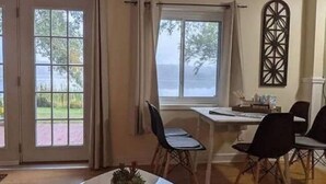 Ein Essbereich mit Tisch und Stühlen, ein Fenster mit Vorhängen und Blick ins Freie.