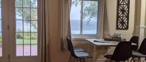A dining area with a table and chairs, a window with curtains, and a view of the outdoors.