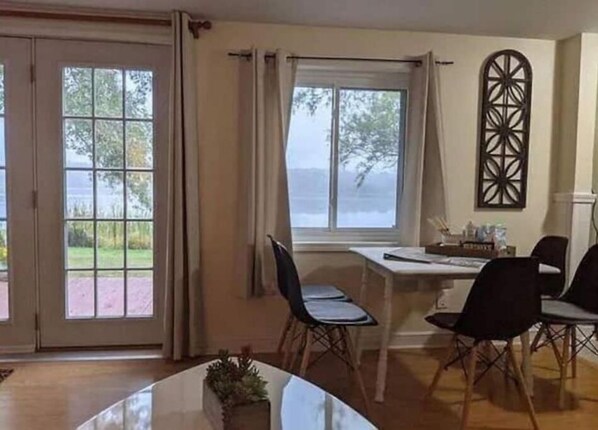 Uma área de refeições com uma mesa e cadeiras, uma janela com cortinas e vista para o exterior.