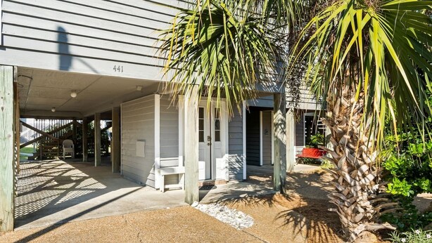A single-story building with a covered porch, a bench, and a palm tree. - Cozy Dog-Friendly Cottage · Steps to Gulf Beach (Port St. Joe)