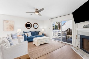 A living room with a white sofa, blue sofa, white coffee table, and a fireplace. - Cozy Dog-Friendly Cottage · Steps to Gulf Beach · Sleeps 4 (Port St. Joe)