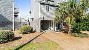 A residential building with a covered entryway, a small garden with a palm tree, and a fenced area. - Cozy Dog-Friendly Cottage · Steps to Gulf Beach (Port St. Joe)