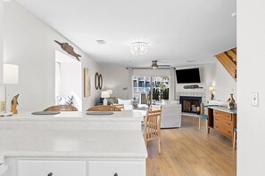 A spacious living area with a large island, a fireplace, and a view of the outdoors. - Cozy Dog-Friendly Cottage · Steps to Gulf Beach (Port St. Joe)