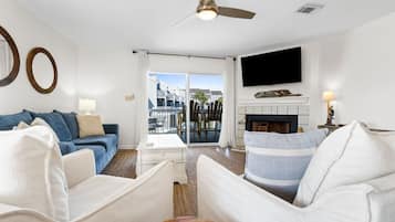 A living room with a sofa, armchair, and a flat-screen TV mounted on the wall.