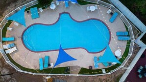Vista aerea di una piscina circondata da poltrona relax e una zona solarium.