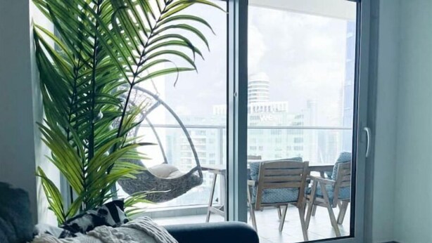 Een moderne woonkamer met een groot raam, een hangstoel, een bank en een bijzettafeltje.