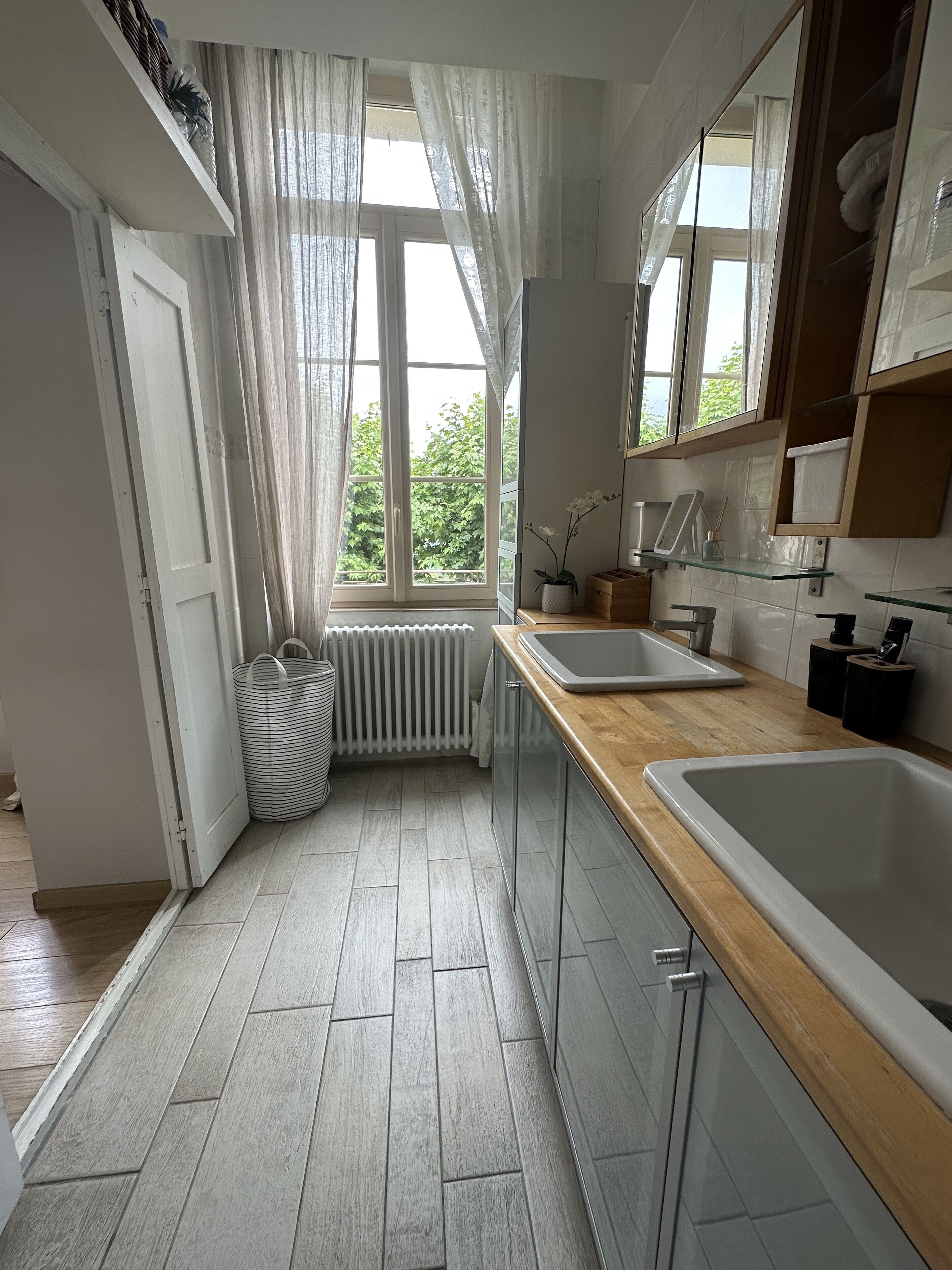 A modern kitchen with a large window, wooden countertop, and a built-in oven.