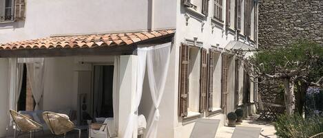 A white villa with a tiled roof, a pool, and outdoor seating.