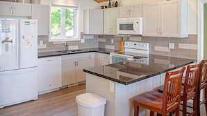A modern kitchen with white cabinets, a granite countertop, a built-in oven, and a window providing natural light.