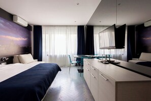 A hotel room with a bed, desk, chair, and a TV.