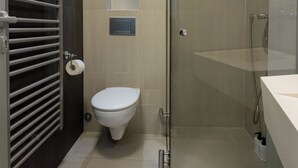Un baño moderno con cabina de ducha de vidrio, un inodoro y una toalla en el suelo.