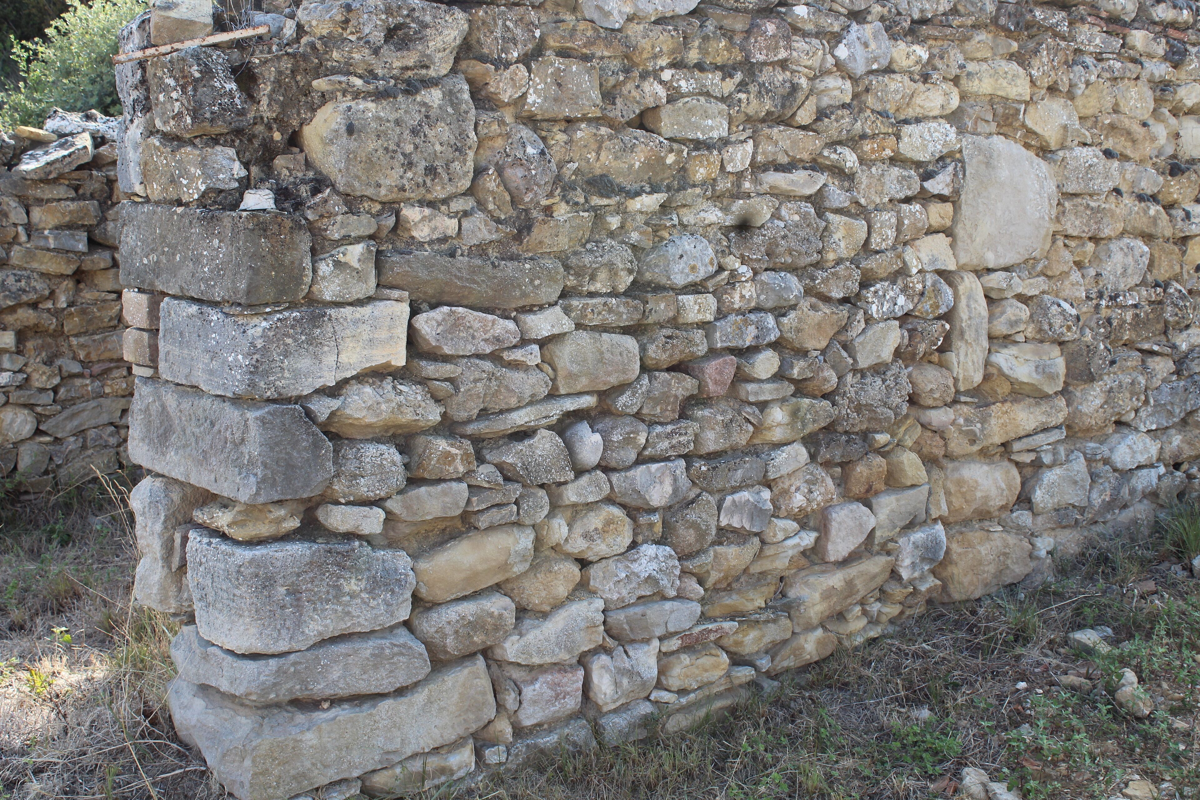 Un mur de pierres, composé de pierres de différentes tailles, disposées de manière aléatoire.