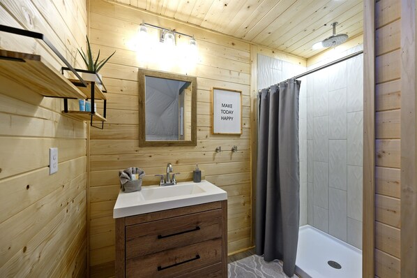 A wooden-paneled bathroom with a white sink, wooden cabinet, mirror, and shower curtain.