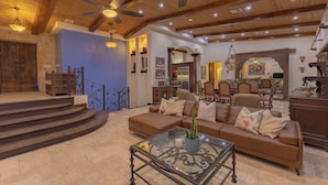A spacious living area with a wooden ceiling, a large brown leather sofa, a glass coffee table, and a staircase leading to an upper level. - Papagayo Ocean View Luxury Villa (Carrillo Guanacaste)