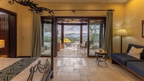 A hotel room with a bed, a sofa, a table, and a view of the outdoors. - Papagayo Ocean View Luxury Villa (Carrillo Guanacaste)