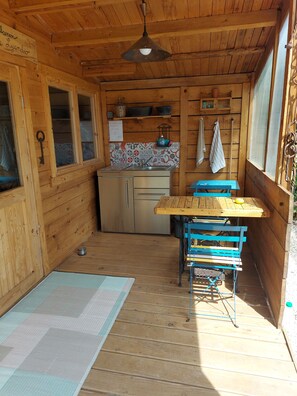 Una cabaña de madera con zona de cocina, una mesa de comedor y un pequeño rincón de estar.