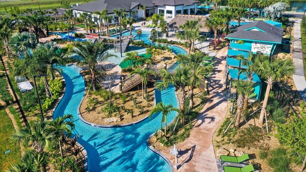 Een resort met een groot zwembad, palmbomen en moderne gebouwen.