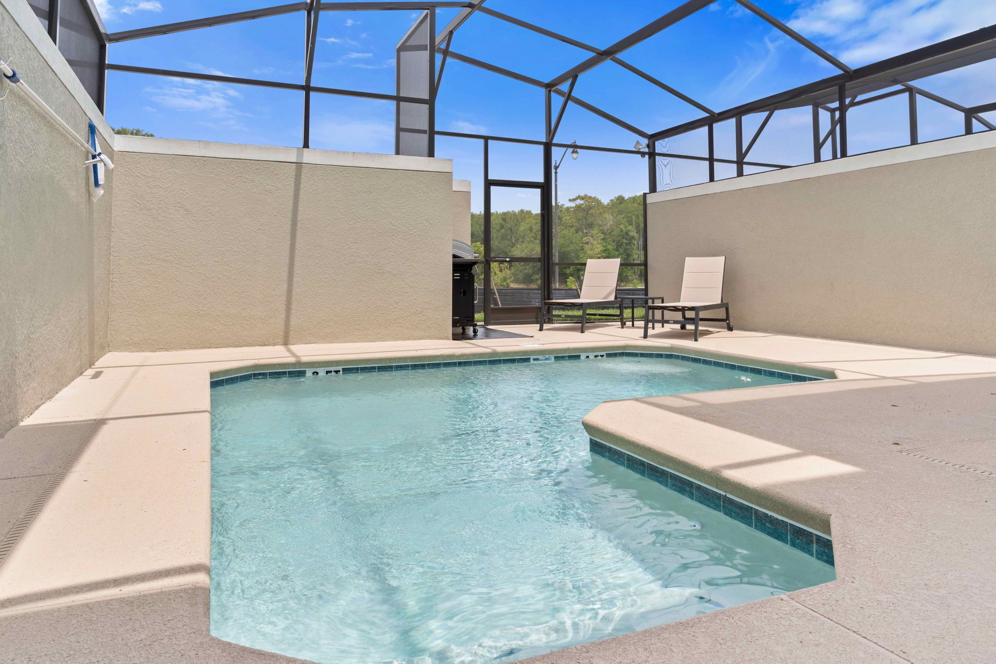 A rectangular indoor pool with clear blue water, surrounded by beige walls and a glass enclosure.