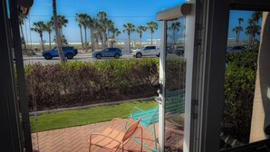Blick vom Balkon auf einen Parkplatz mit Palmen und einem Strand im Hintergrund.
