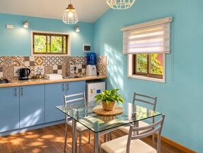 A modern kitchen with blue cabinets, a glass dining table, and a coffee maker. - Fully equipped cabin (Isla de Pascua)