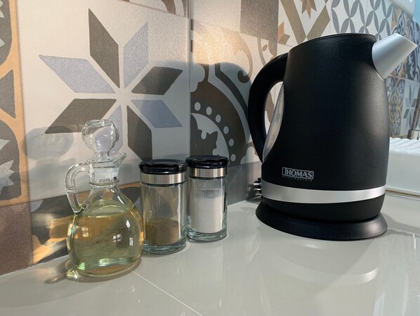 A kitchen area with a black electric kettle, a glass decanter, and two salt and pepper shakers. - Fully equipped cabin (Isla de Pascua)
