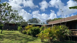 A property with a grassy lawn, a wooden cabin, and a building with a brown roof. - Comfortable and equipped cabin (Isla de Pascua)