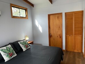 Une chambre à coucher avec un lit, une table de chevet, une fenêtre et des portes en bois.