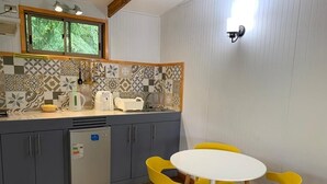 A compact kitchen with a refrigerator, a sink, and a window above the counter. There is a round table with four chairs. - Comfortable and equipped cabin (Isla de Pascua)